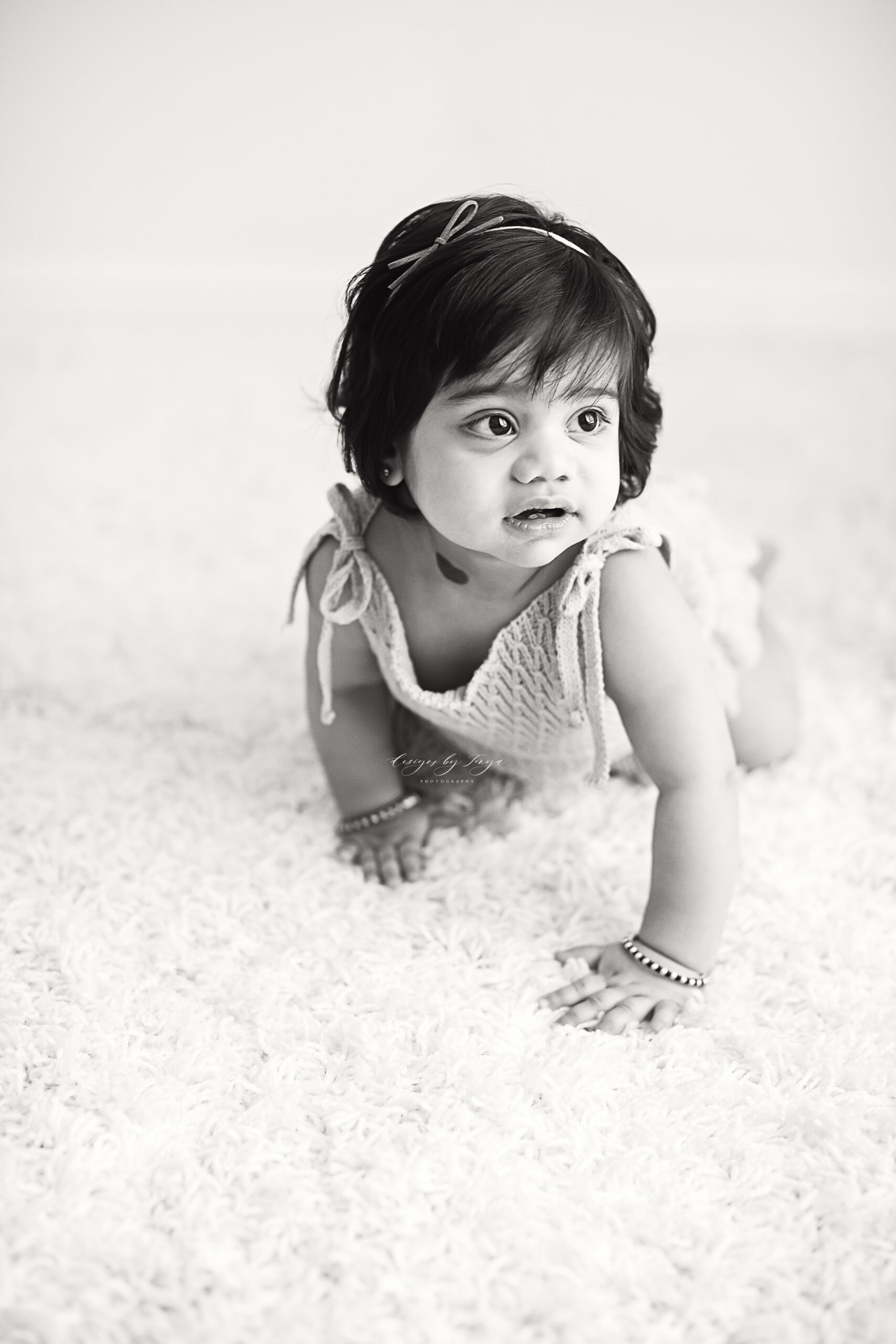 one year baby girl crawling on a rug black and white photo