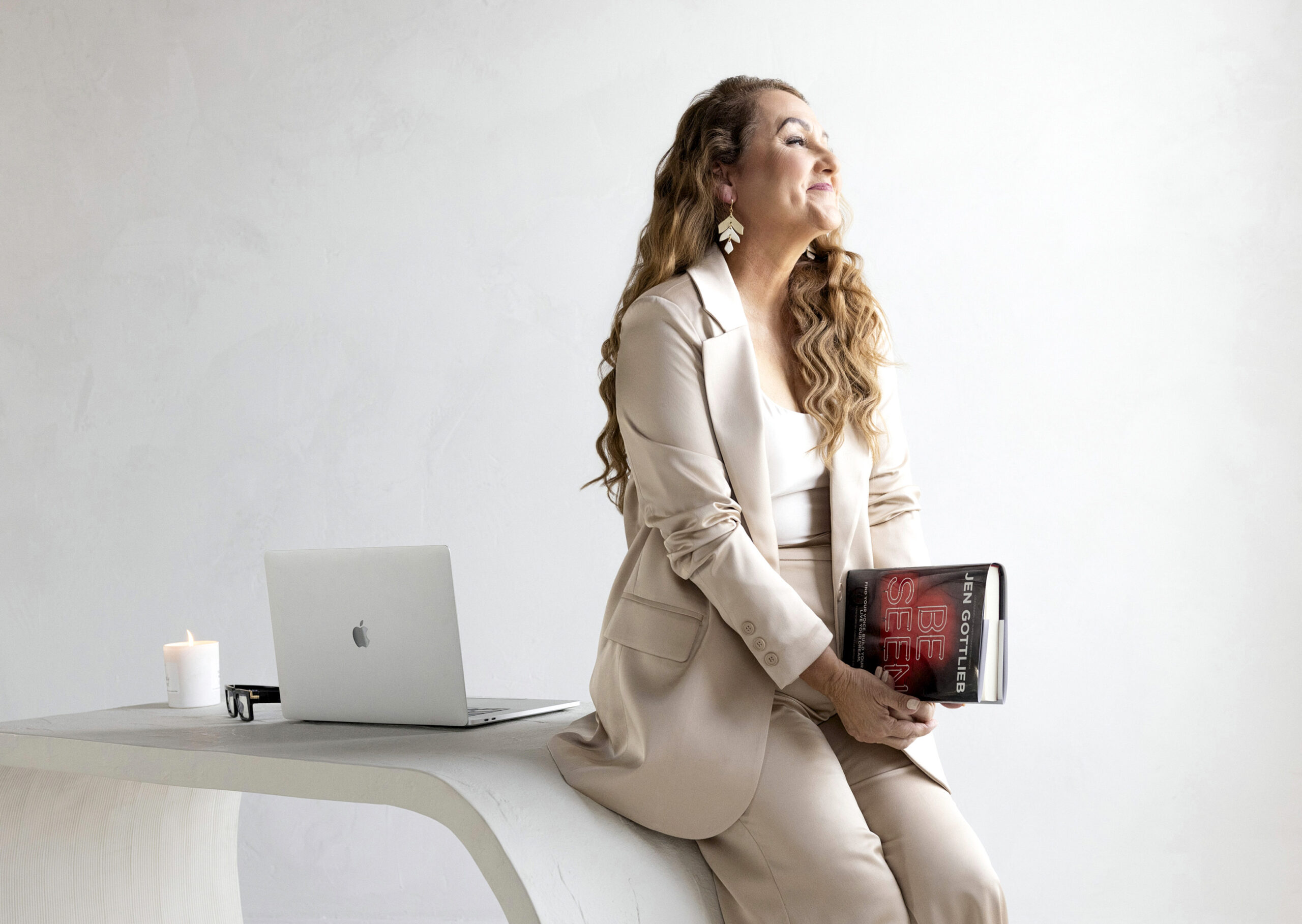 Brand Photographer Tonya Riggs holds Be Seen book by Jen Gottlieb leaning up against desk with computer